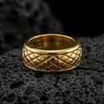 Load image into Gallery viewer, Gold plated quilted diamond pattern band ring on volcanic rock, detailed raised grid texture and clean borders, luxury jewelry product photography.
