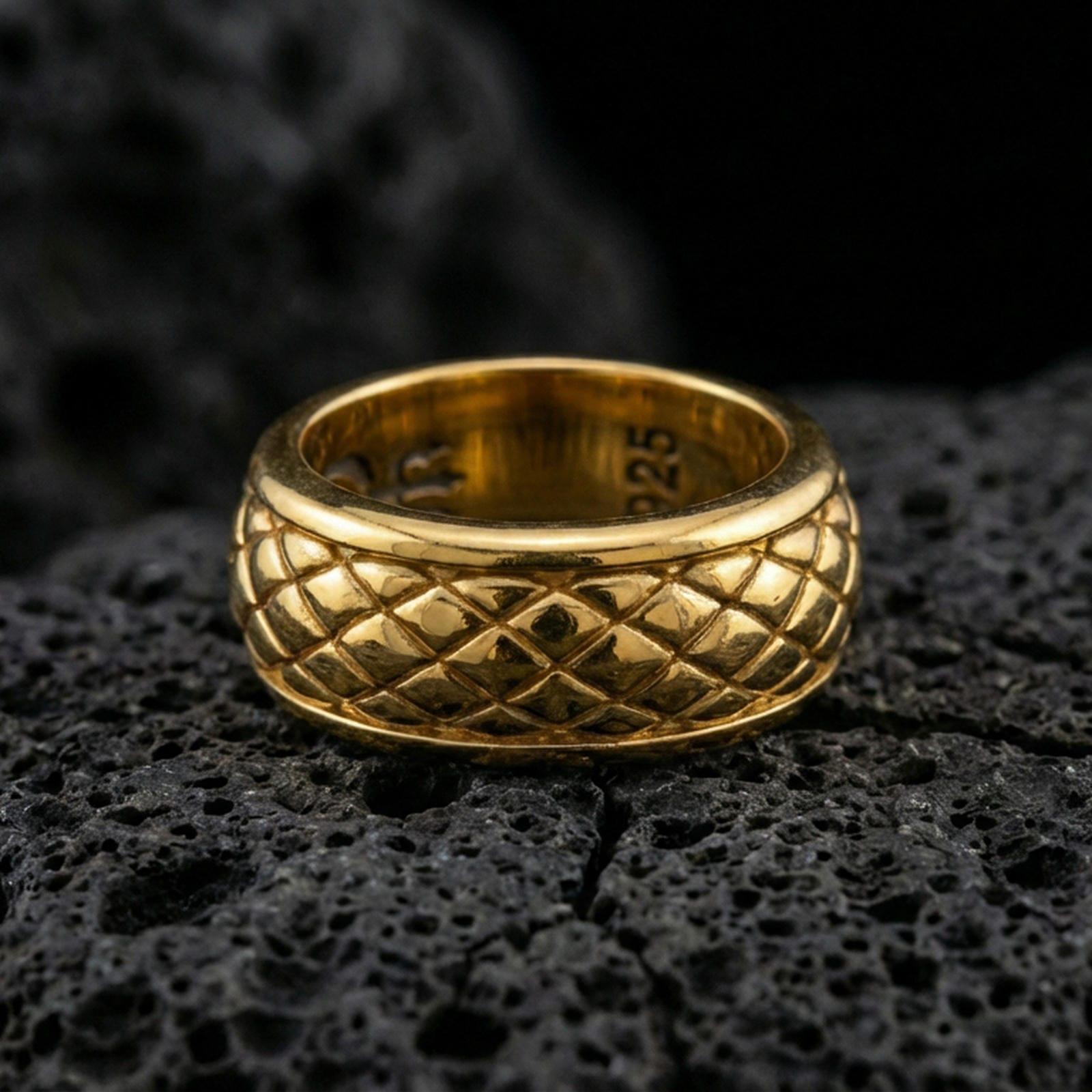 Gold plated quilted diamond pattern band ring on volcanic rock, detailed raised grid texture and clean borders, luxury jewelry product photography.