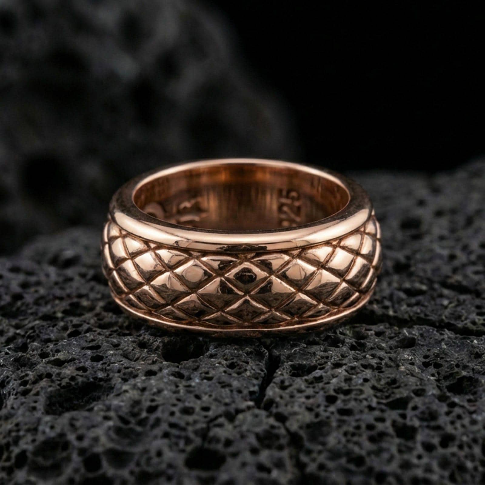 Rose gold plated sterling silver quilted band on volcanic stone, sculpted diamond grid texture with deep contrast, minimal high-end close-up.