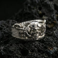 Load image into Gallery viewer, Polished silver steampunk skull statement ring on black volcanic stone, crisp skull and gear-inspired details with textured band, centered close-up studio lighting.
