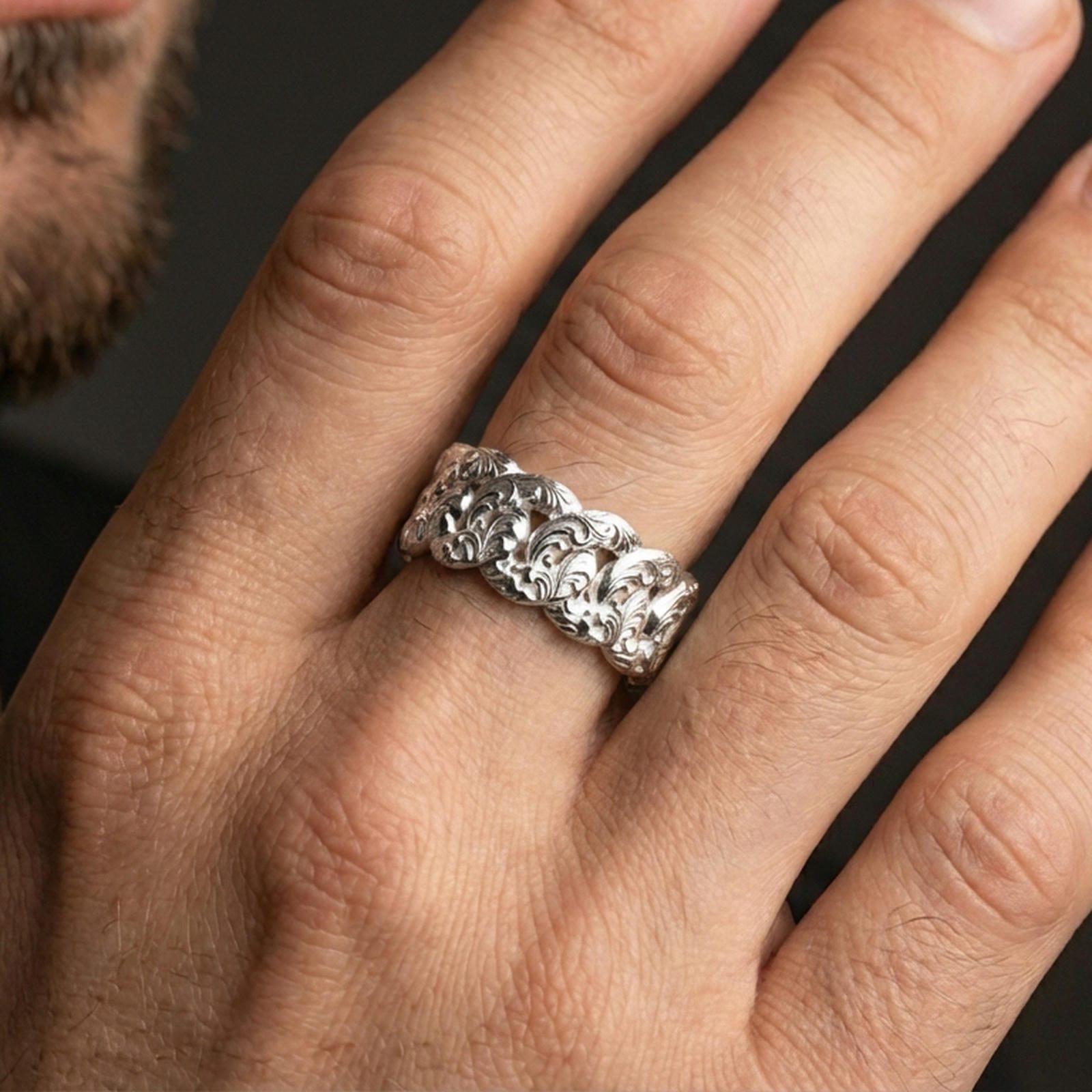 Polished silver Cuban link band ring on finger, crisp interlocking chain links with ornate texture, refined everyday wear close-up.