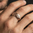 Load image into Gallery viewer, Rose gold plated floral pattern band ring worn on finger, ornate flower motif with scroll engraving, elegant lifestyle wear shot.
