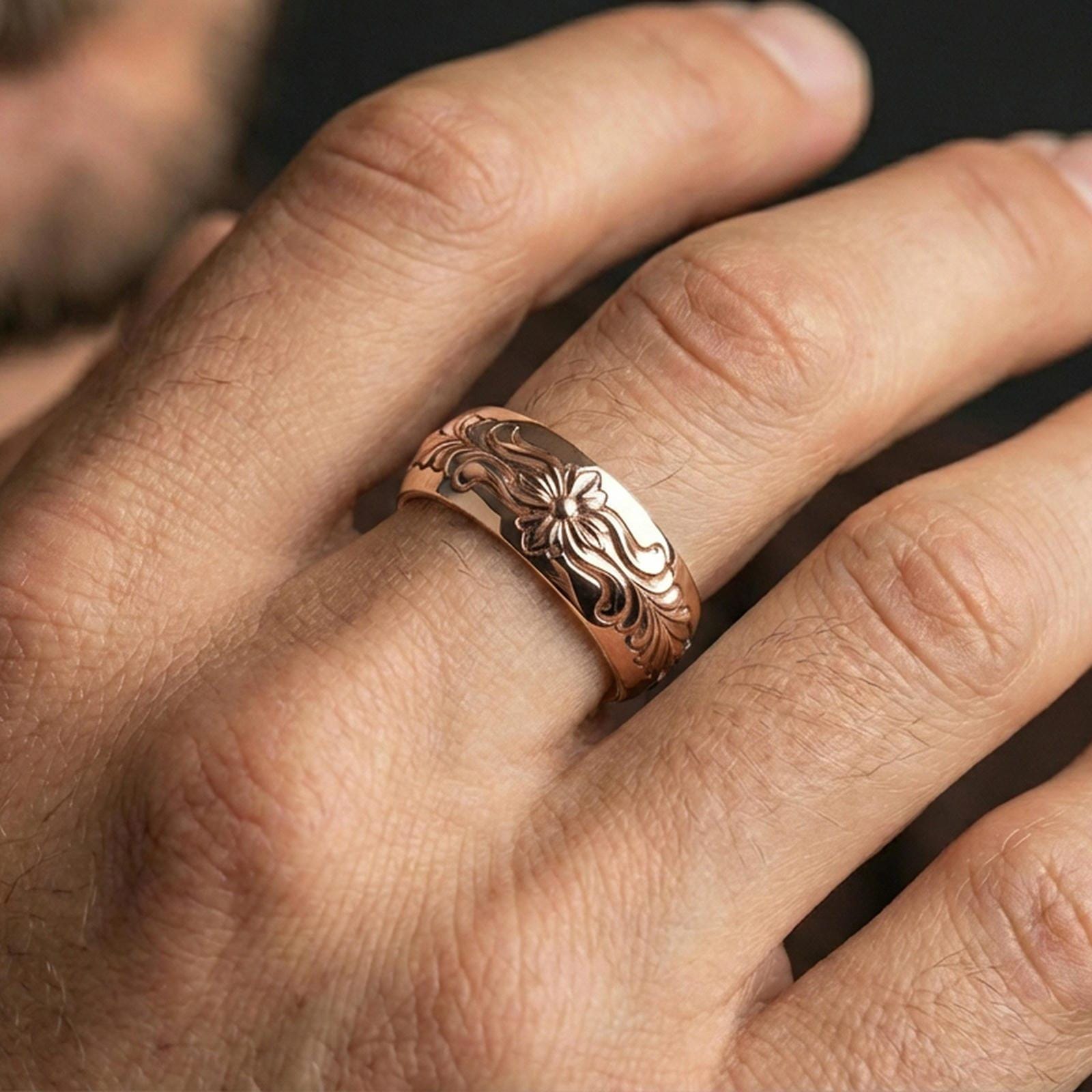 Rose gold plated floral pattern band ring worn on finger, ornate flower motif with scroll engraving, elegant lifestyle wear shot.