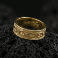 Load image into Gallery viewer, Gold plated scrollwork engraved band ring on volcanic rock, detailed swirl motif with beaded border trim, luxury jewelry product photography.

