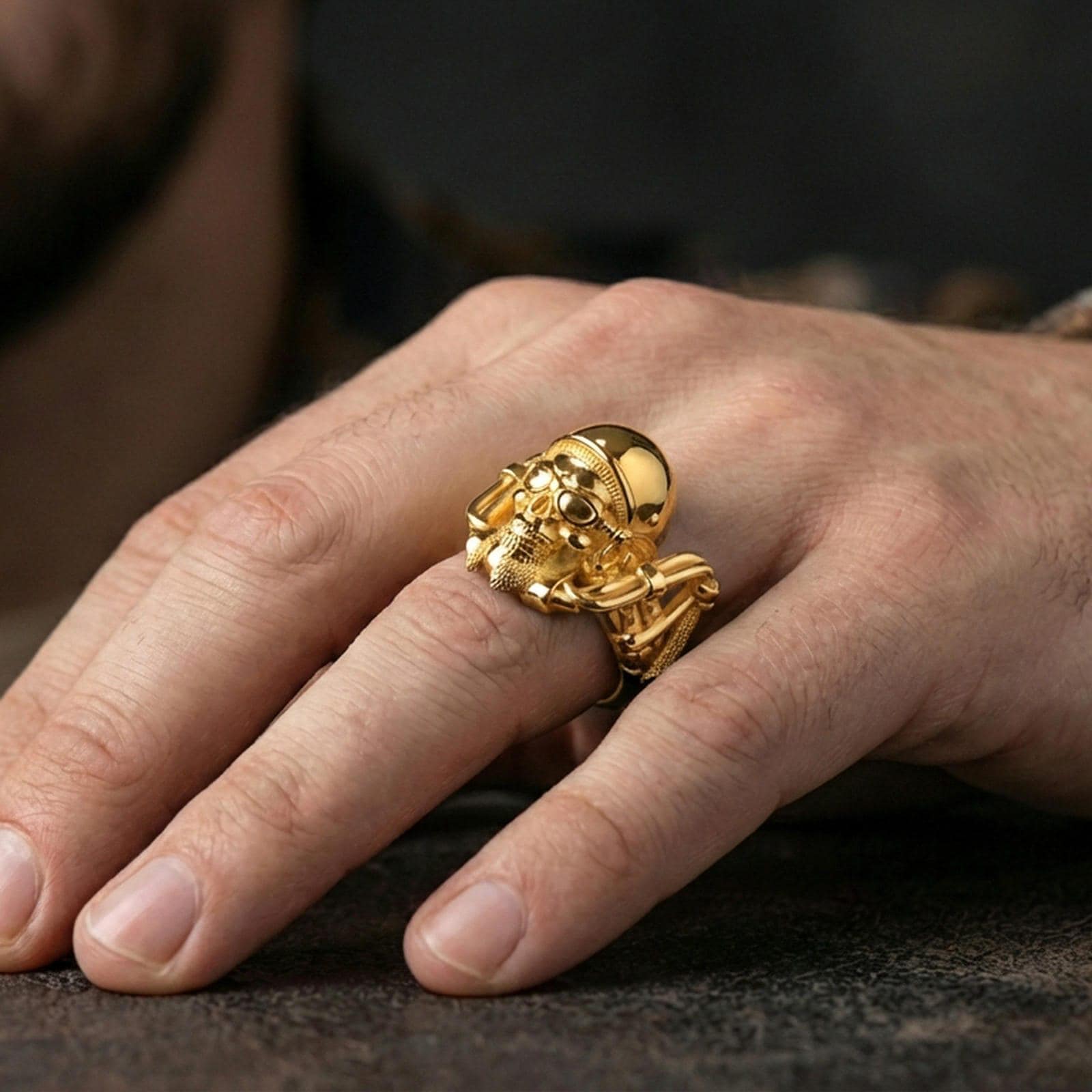 Gold plated biker skull ring worn on finger, detailed helmet and goggles with rugged skull relief, premium lifestyle jewelry photo.