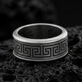 Load image into Gallery viewer, Oxidized sterling silver Greek key band ring on dark volcanic rock, bold meander pattern engraving with smooth comfort edges, premium macro product shot.
