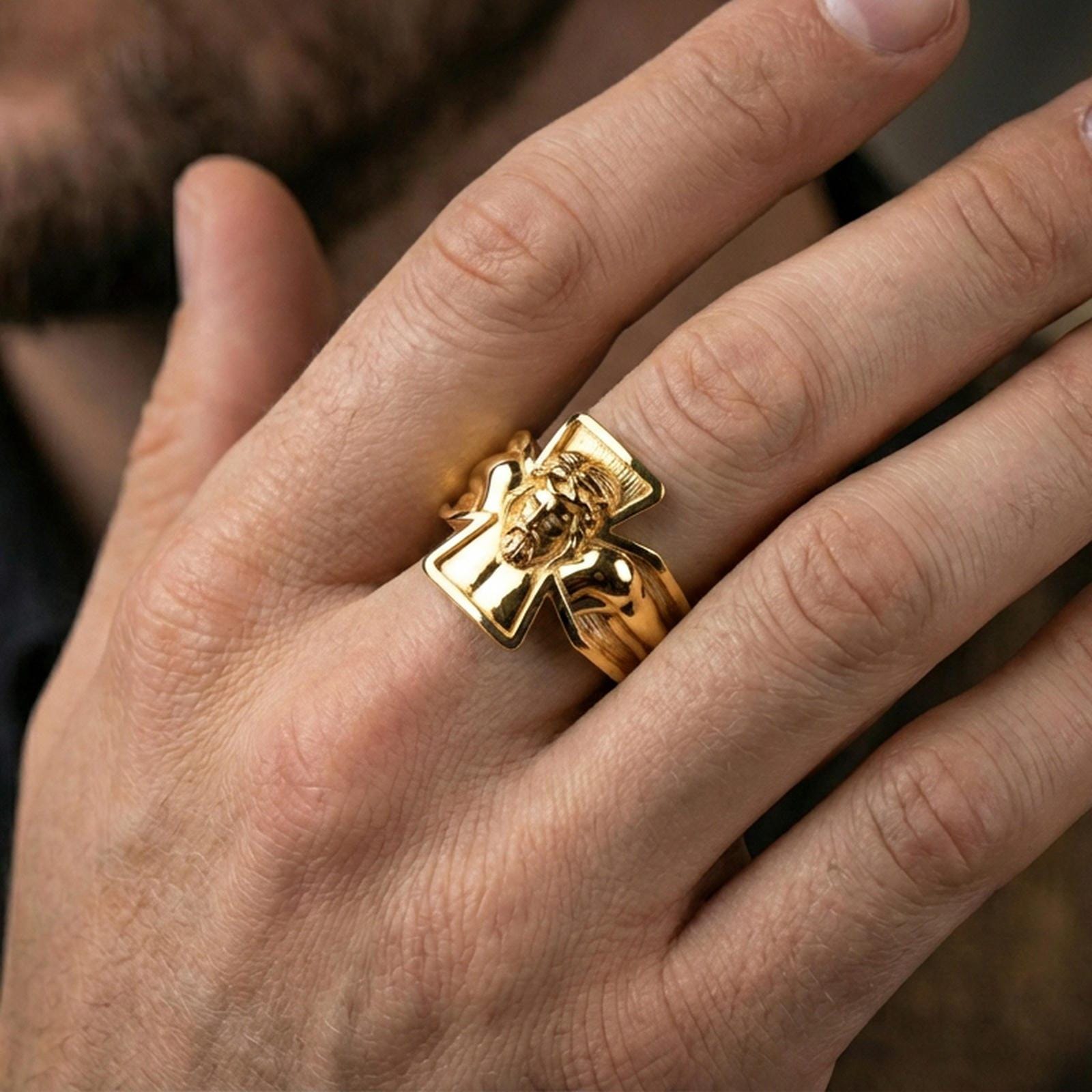 Gold plated crucifix Jesus ring worn on finger, detailed Christ relief with bold cross frame, premium lifestyle jewelry photo.