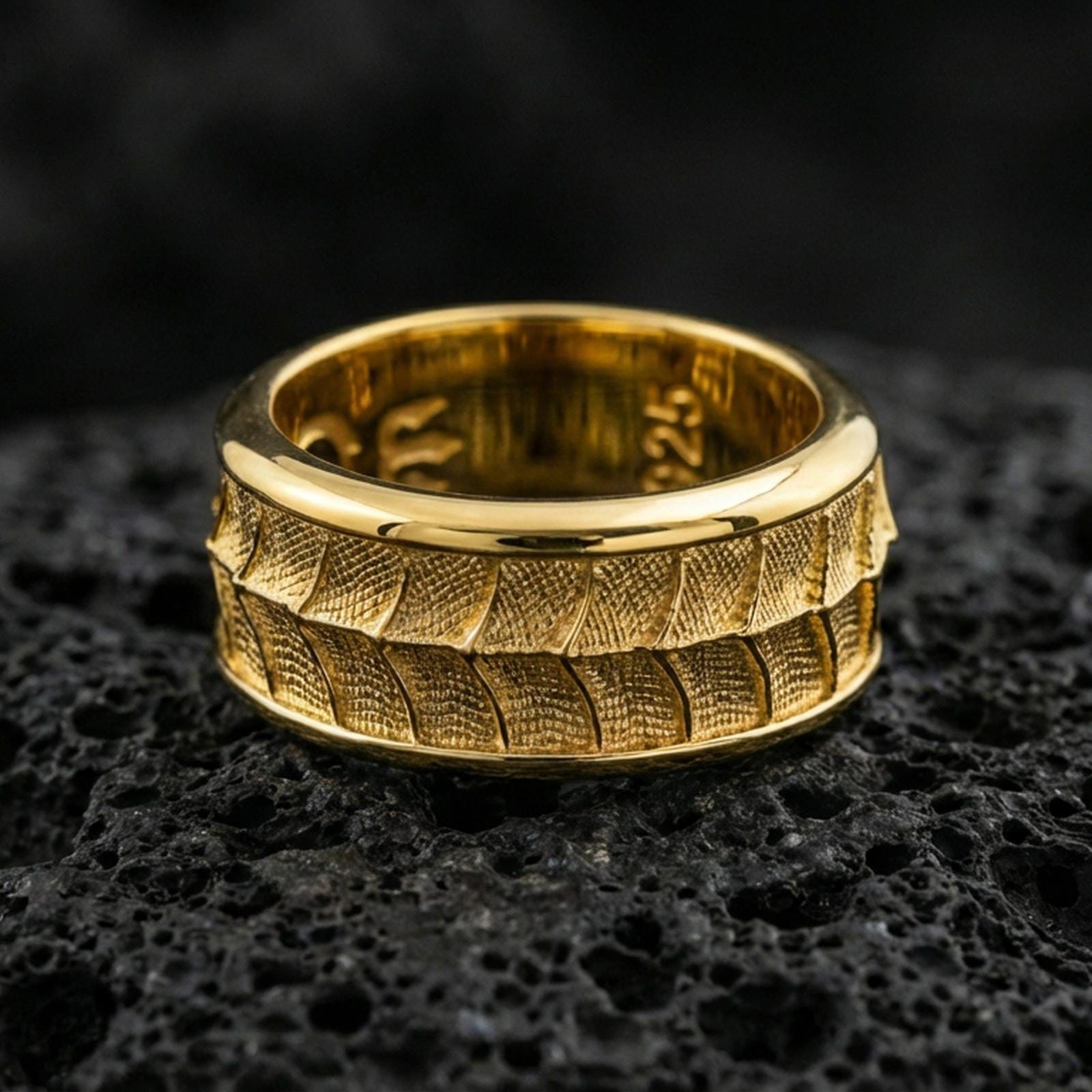 Gold plated lizard scale spinner band ring on volcanic rock, detailed reptile pattern on rotating band, luxury jewelry product photography.