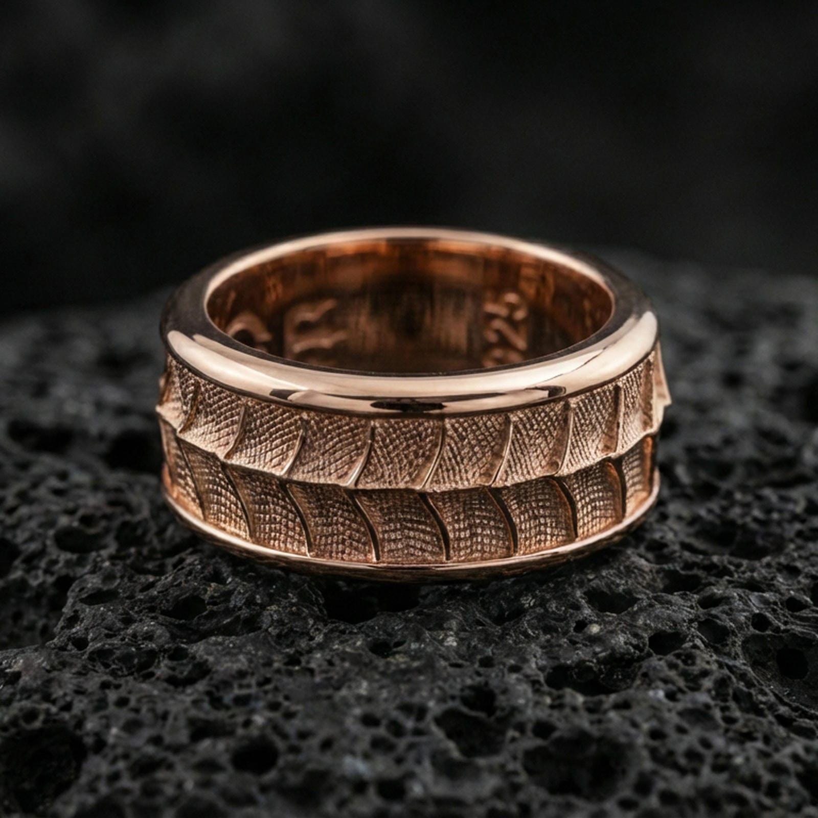 Rose gold plated sterling silver lizard scale spinner ring on volcanic stone, bold textured reptile pattern with deep contrast, minimal high-end close-up.