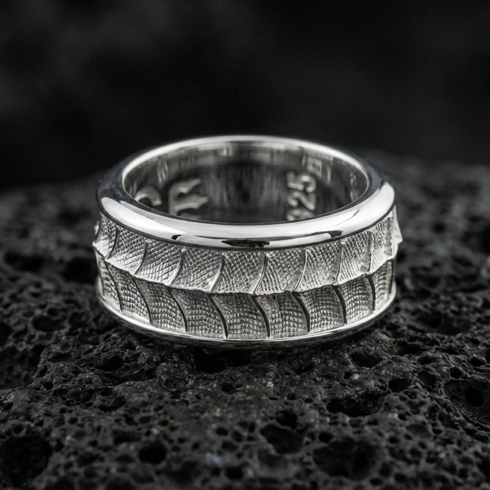 Polished silver lizard scale fidget spinner ring on black volcanic stone, crisp reptile texture detail with smooth comfort edges, centered close-up studio lighting.