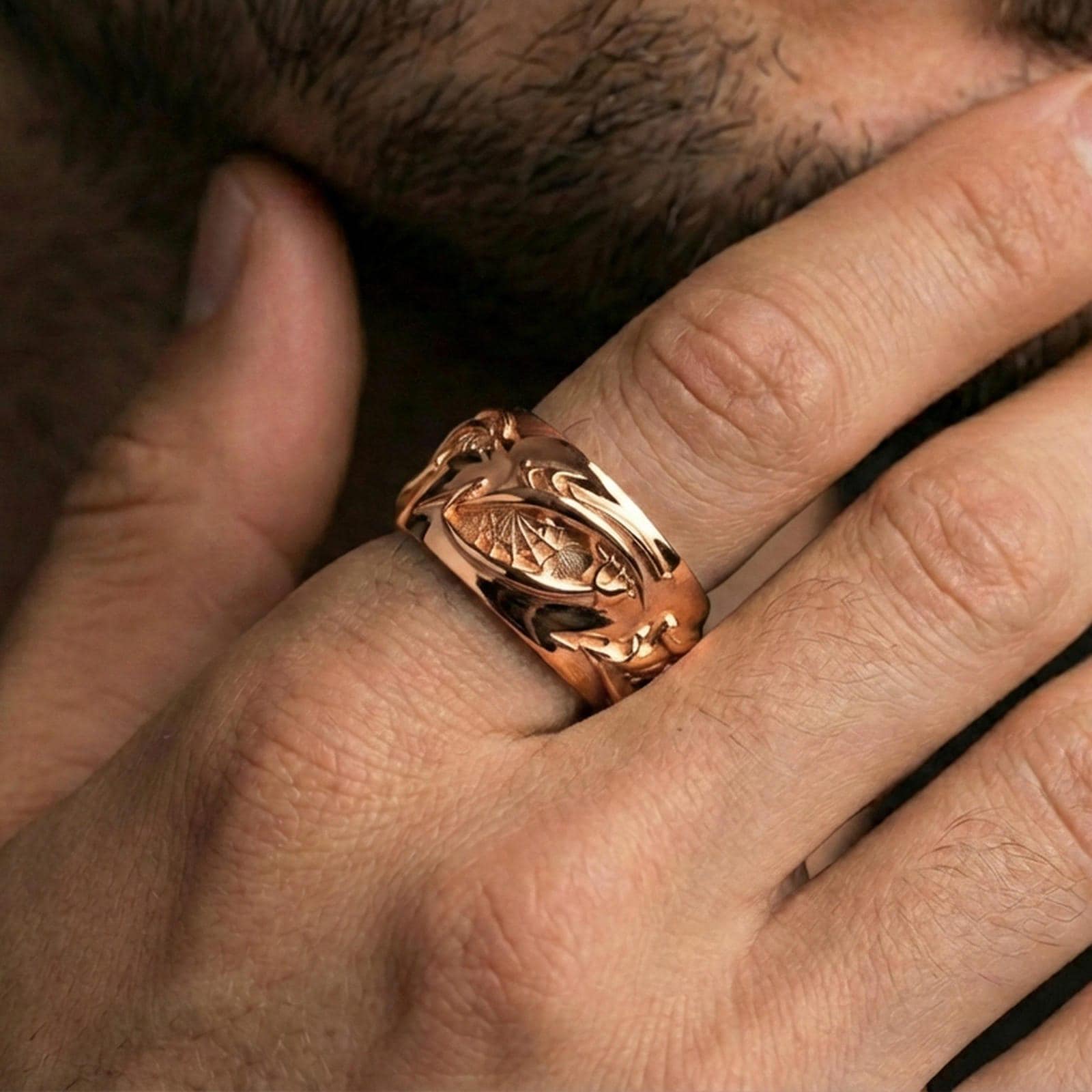 Rose gold plated roots band ring worn on finger, sculpted vine and root relief detail, elegant lifestyle wear shot.