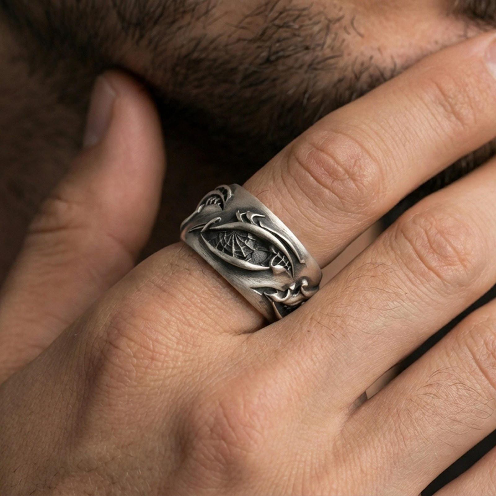 Oxidized sterling silver roots band worn on finger, organic vine relief and bark texture detail, natural lifestyle hand shot with shallow depth of field.