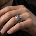 Load image into Gallery viewer, Oxidized sterling silver ornate filigree band worn on finger, floral centerpiece and scroll engraving detail, natural lifestyle hand shot with shallow depth of field.

