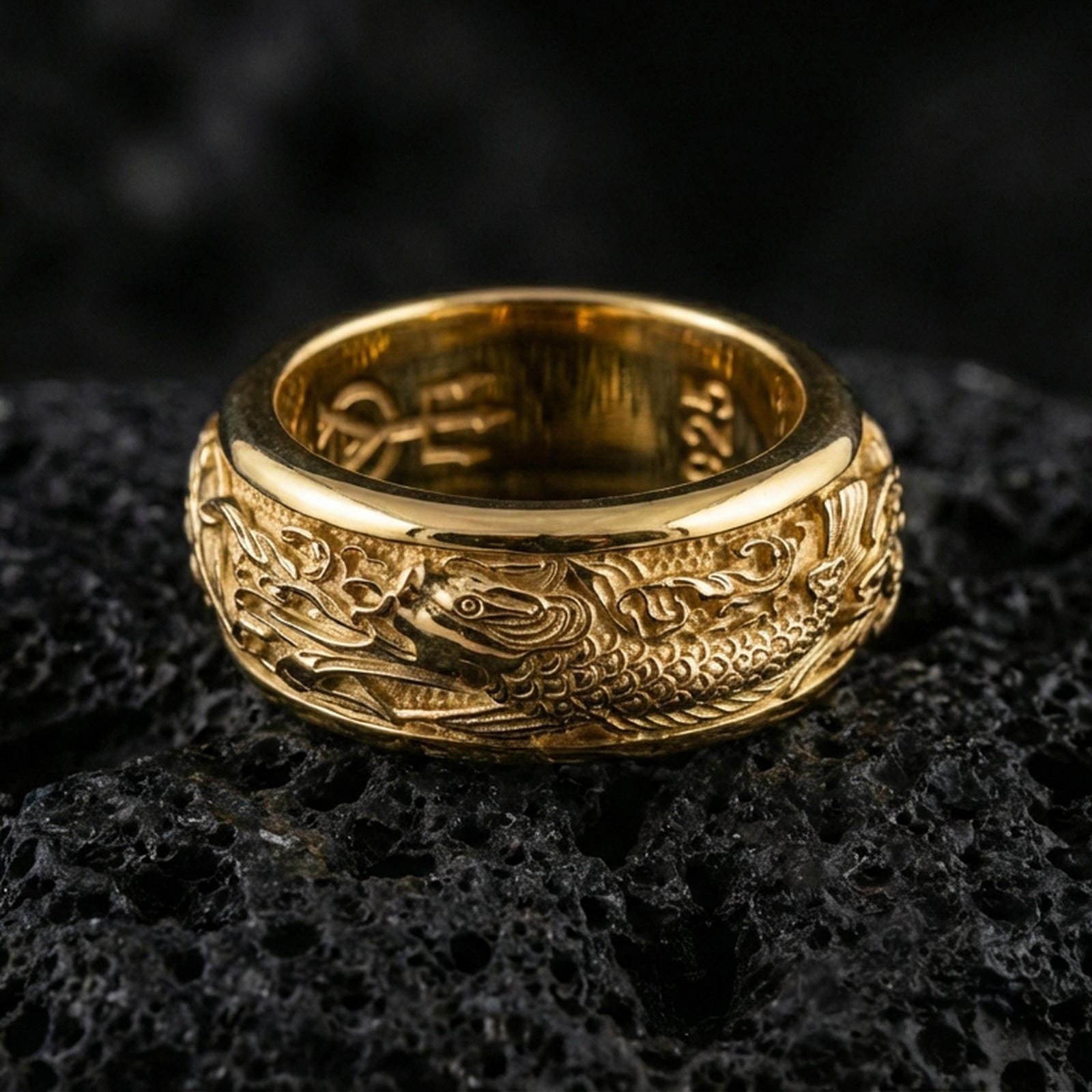 Gold plated koi fish spinner band ring on volcanic rock, detailed koi and ocean wave engraving on rotating band, luxury jewelry product photography.