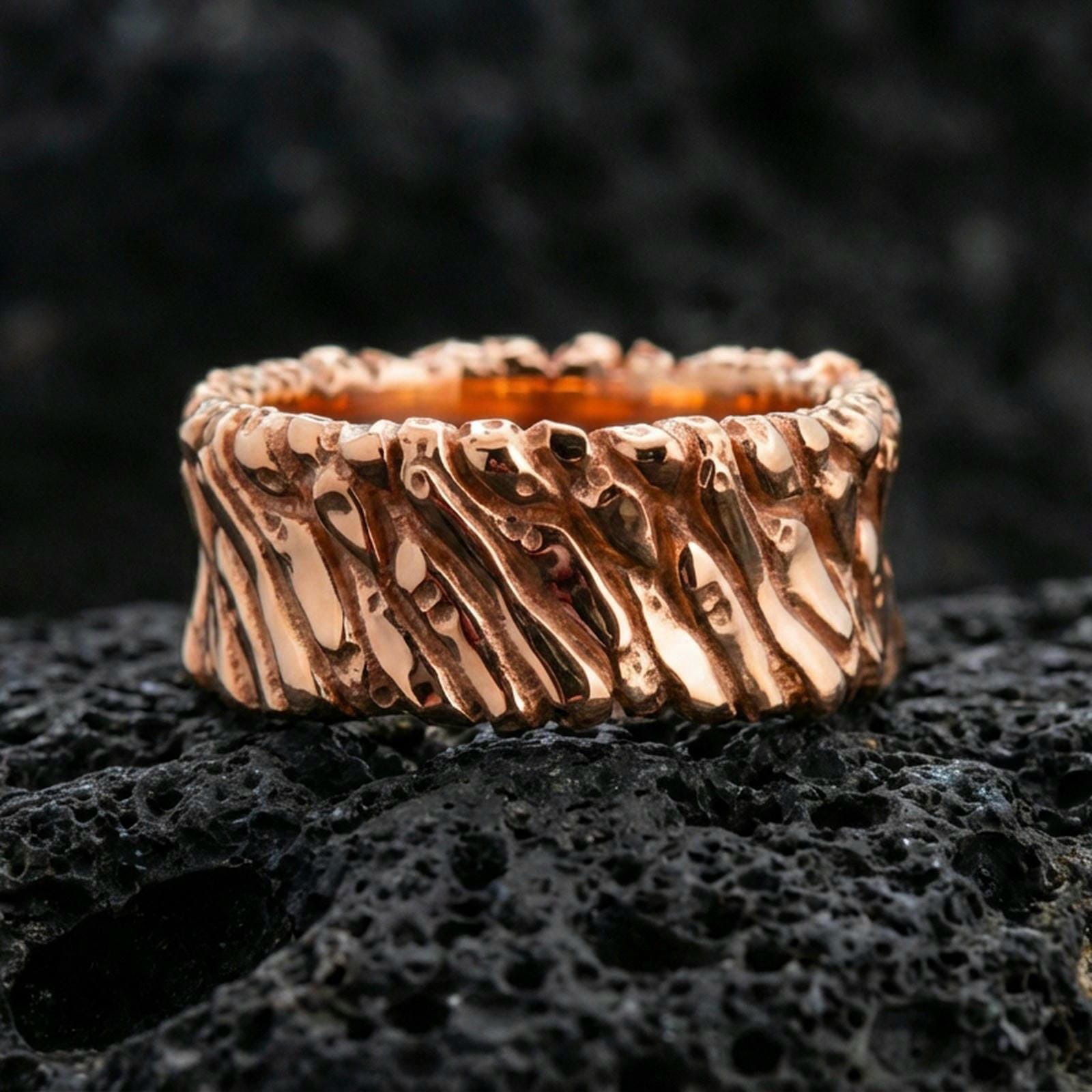 Rose gold plated sterling silver twisted rope band on volcanic stone, sculpted spiral texture with strong contrast and rugged finish, minimal high-end close-up.