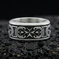 Load image into Gallery viewer, Oxidized sterling silver Maltese cross spinner band ring on dark volcanic rock, raised cross motif on rotating center with ornate side panels, premium macro product shot.
