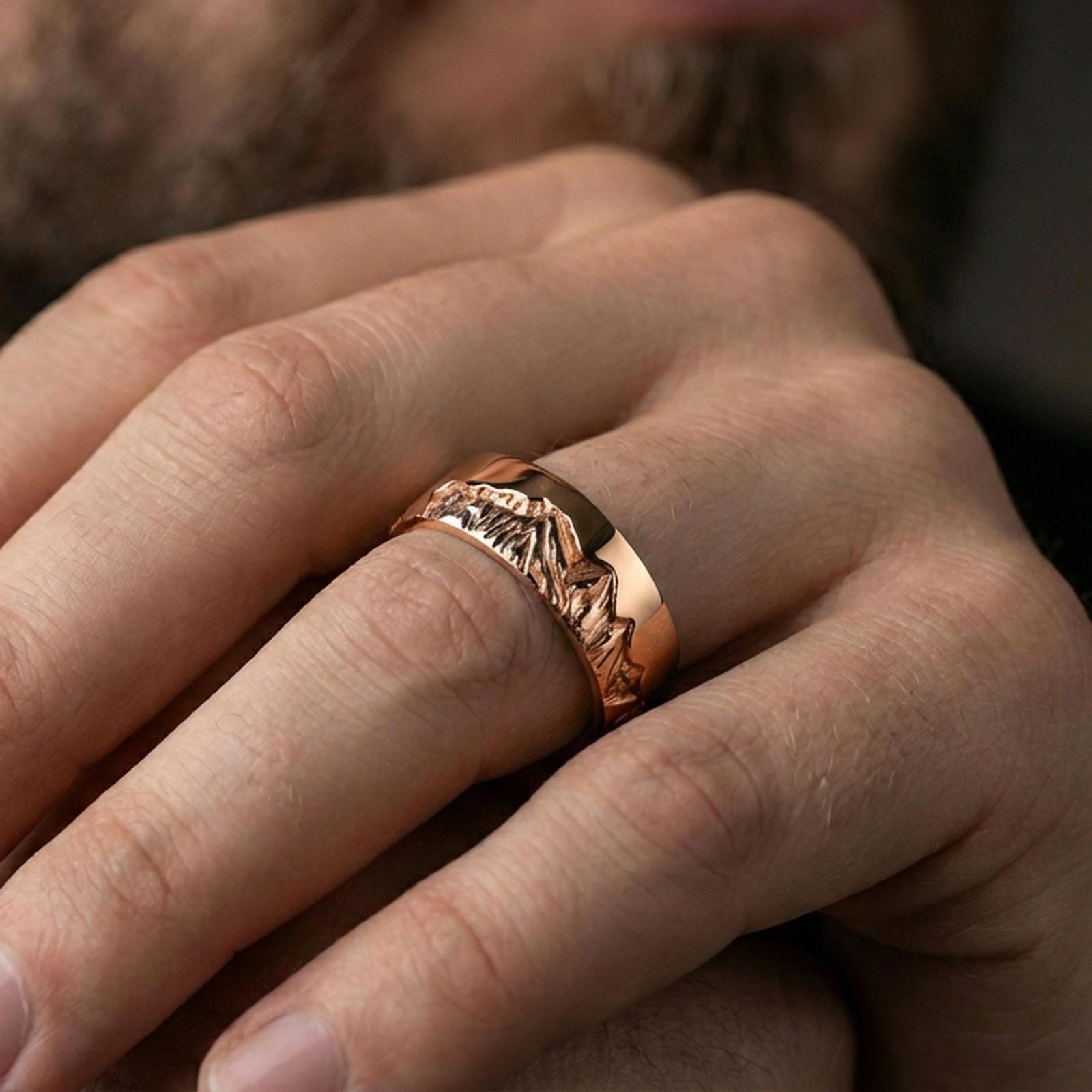 Rose gold plated mountain skyline band ring worn on finger, engraved Grand Teton peaks with rugged detail, elegant lifestyle wear shot.