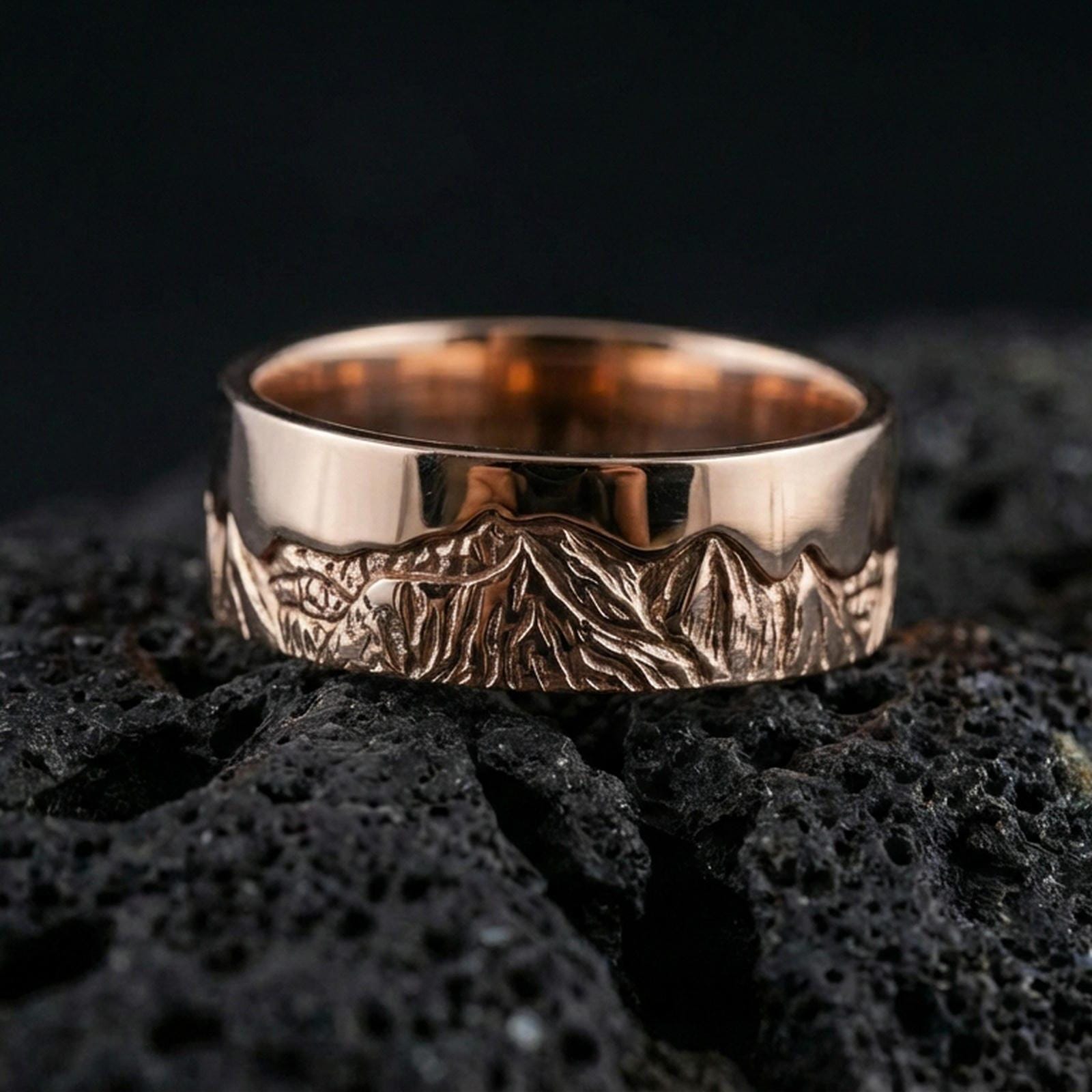 Rose gold plated sterling silver mountain skyline band on volcanic stone, engraved Grand Teton peaks with deep contrast detail, minimal high-end close-up.