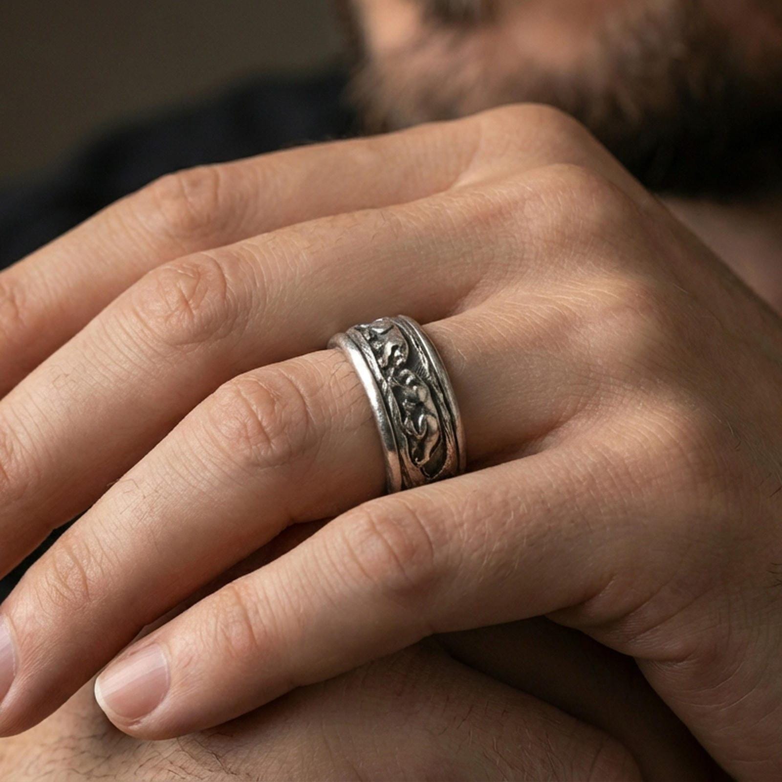 Oxidized sterling silver jaguar spinner band worn on finger, big cat relief detail on rotating center, natural lifestyle hand shot with shallow depth of field.