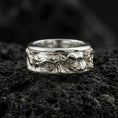 Load image into Gallery viewer, Polished silver Moses fidget spinner ring on black volcanic stone, crisp sculpted portrait relief with ornamental side detailing, centered close-up studio lighting.
