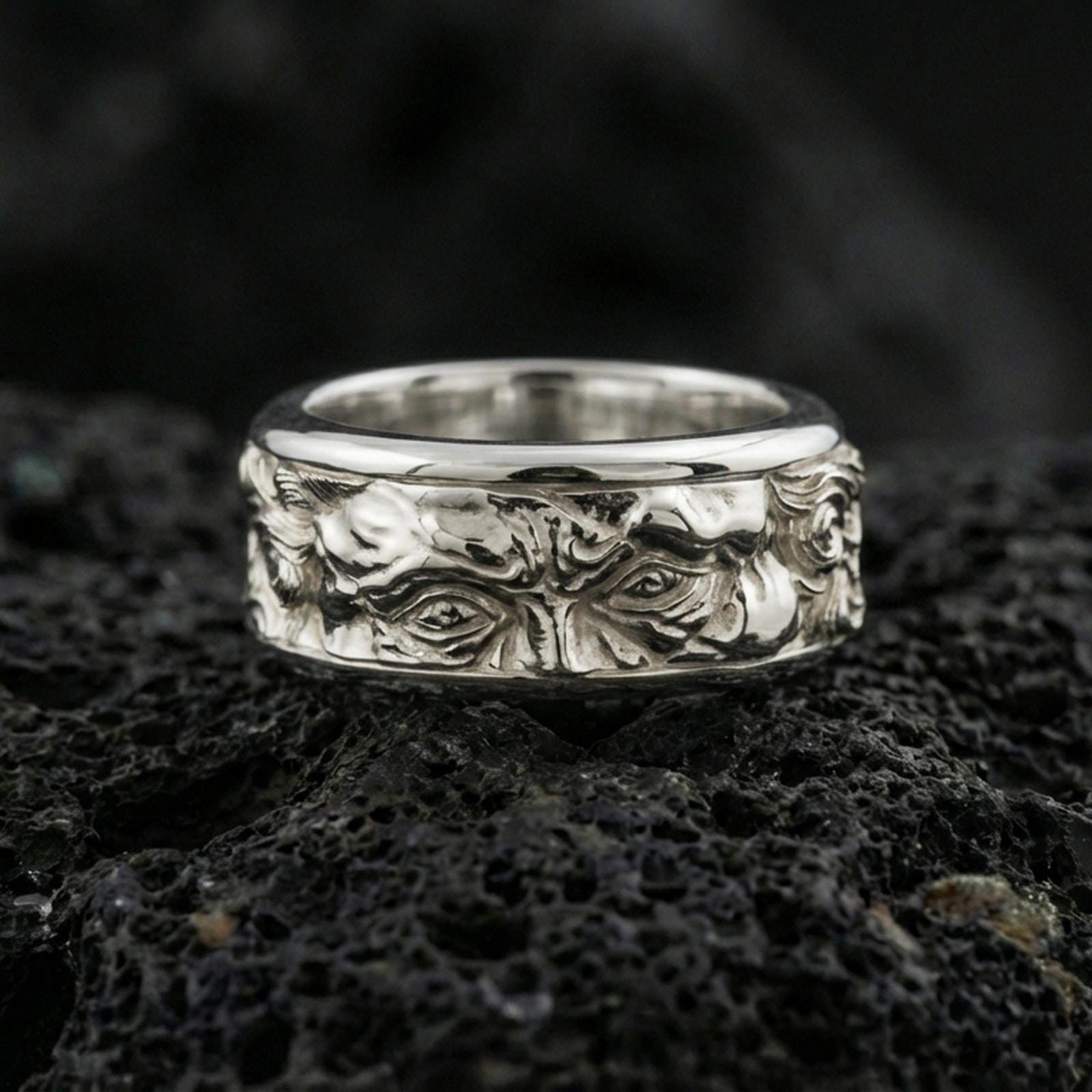 Polished silver Moses fidget spinner ring on black volcanic stone, crisp sculpted portrait relief with ornamental side detailing, centered close-up studio lighting.
