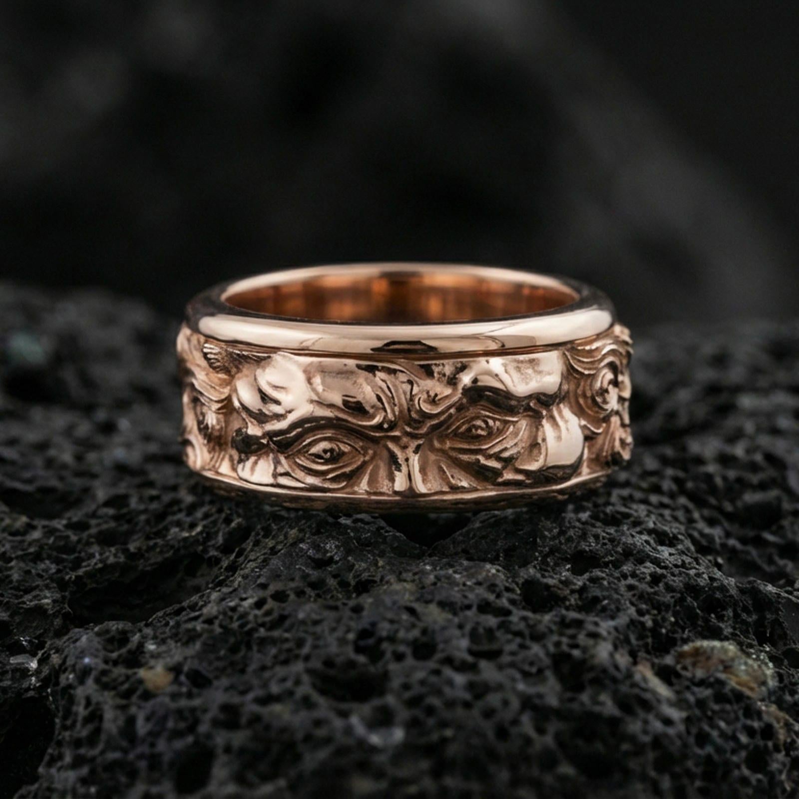 Rose gold plated sterling silver Moses spinner ring on volcanic stone, sculpted Renaissance portrait relief with deep contrast, minimal high-end close-up.