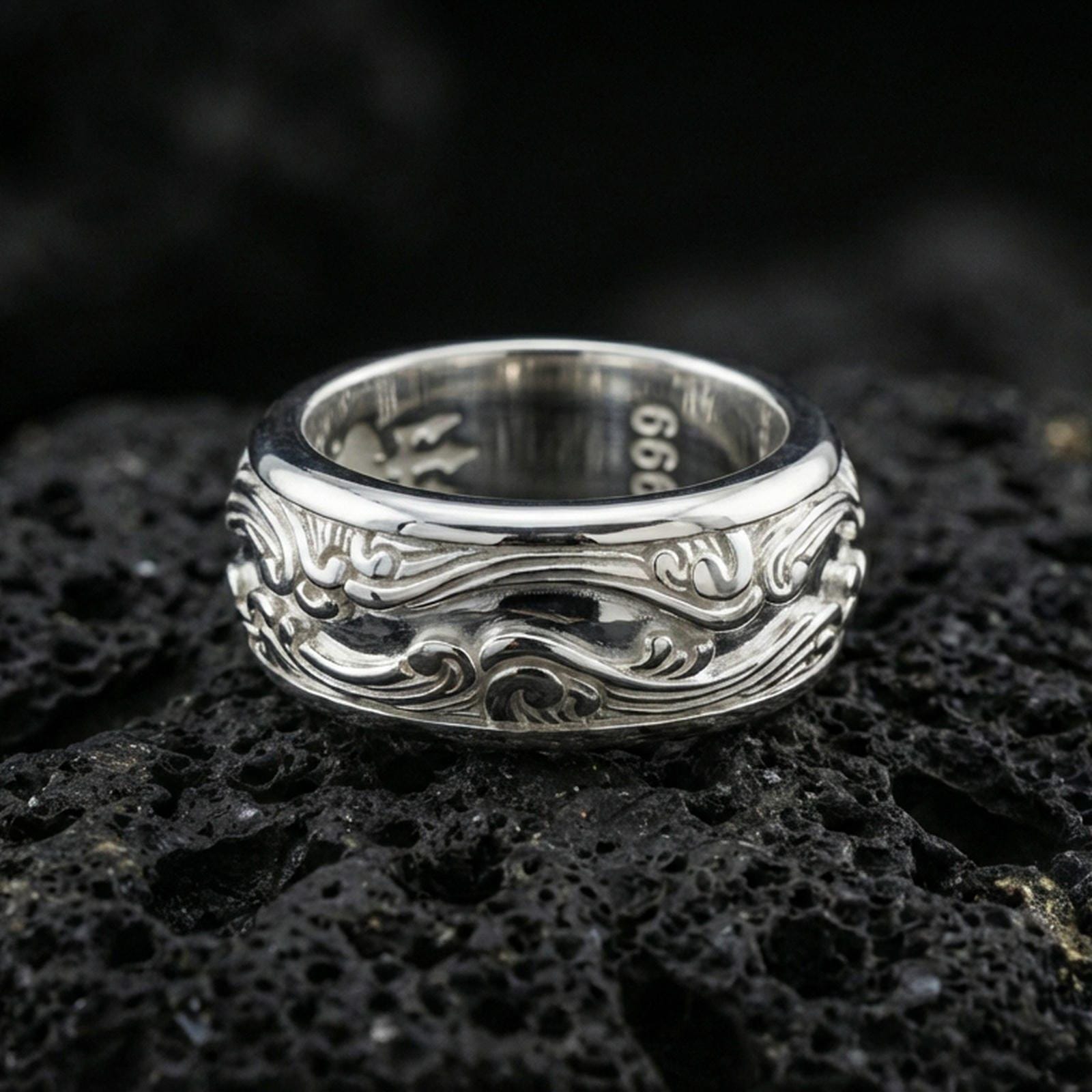 Polished silver wave filigree fidget spinner ring on black volcanic stone, crisp swirling scroll relief with smooth comfort edges, centered close-up studio lighting.