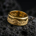 Load image into Gallery viewer, Gold plated mountain range band ring on volcanic rock, detailed alpine skyline engraving with rugged terrain texture, luxury jewelry product photography.
