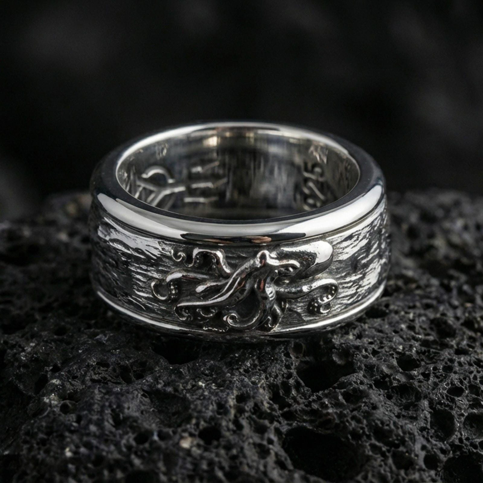 Polished silver octopus fidget spinner ring on black volcanic stone, crisp octopus relief detail with smooth comfort edges, centered close-up studio lighting.