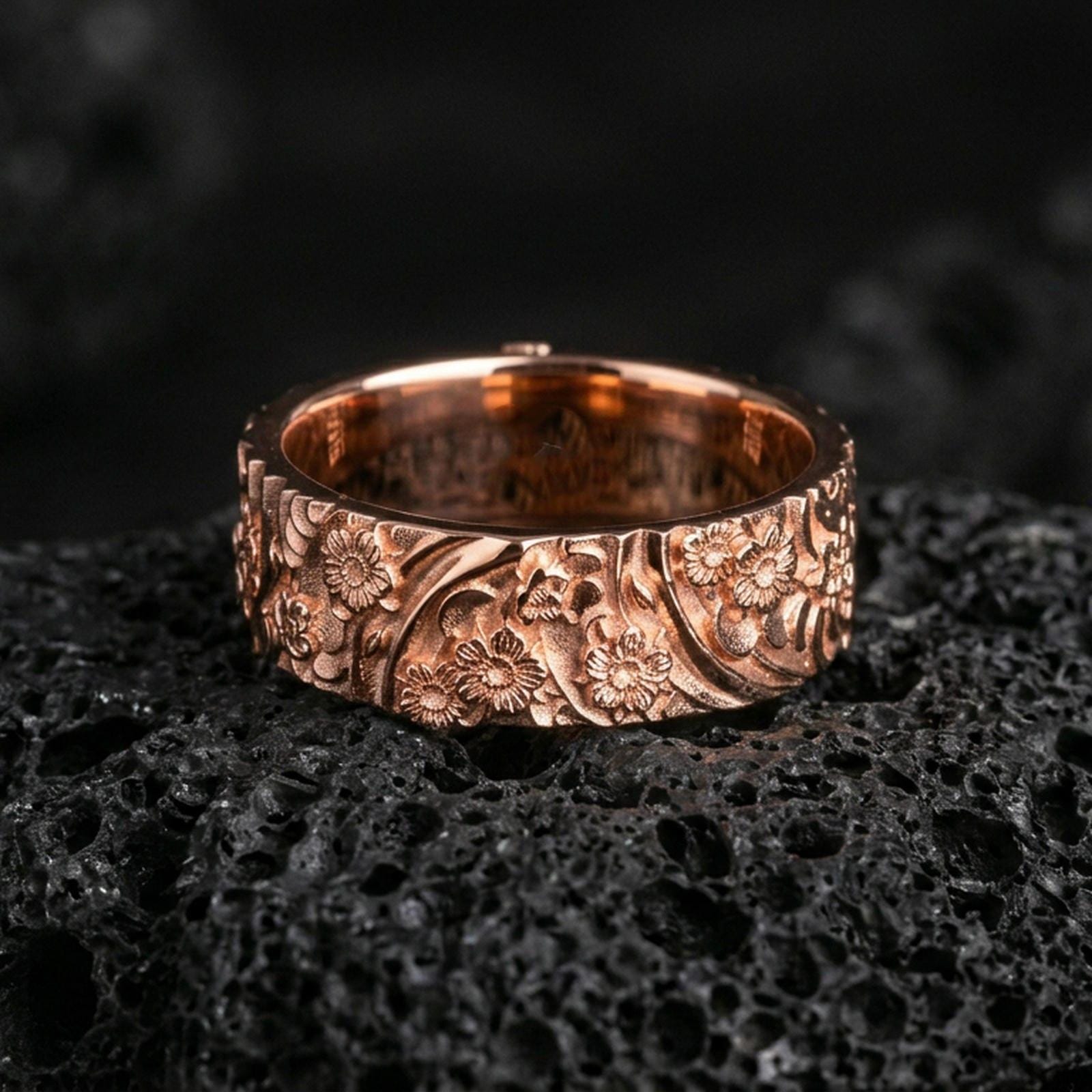 Rose gold plated sterling silver floral pattern band on volcanic stone, sculpted daisy relief with deep contrast and botanical engraving, minimal high-end close-up.