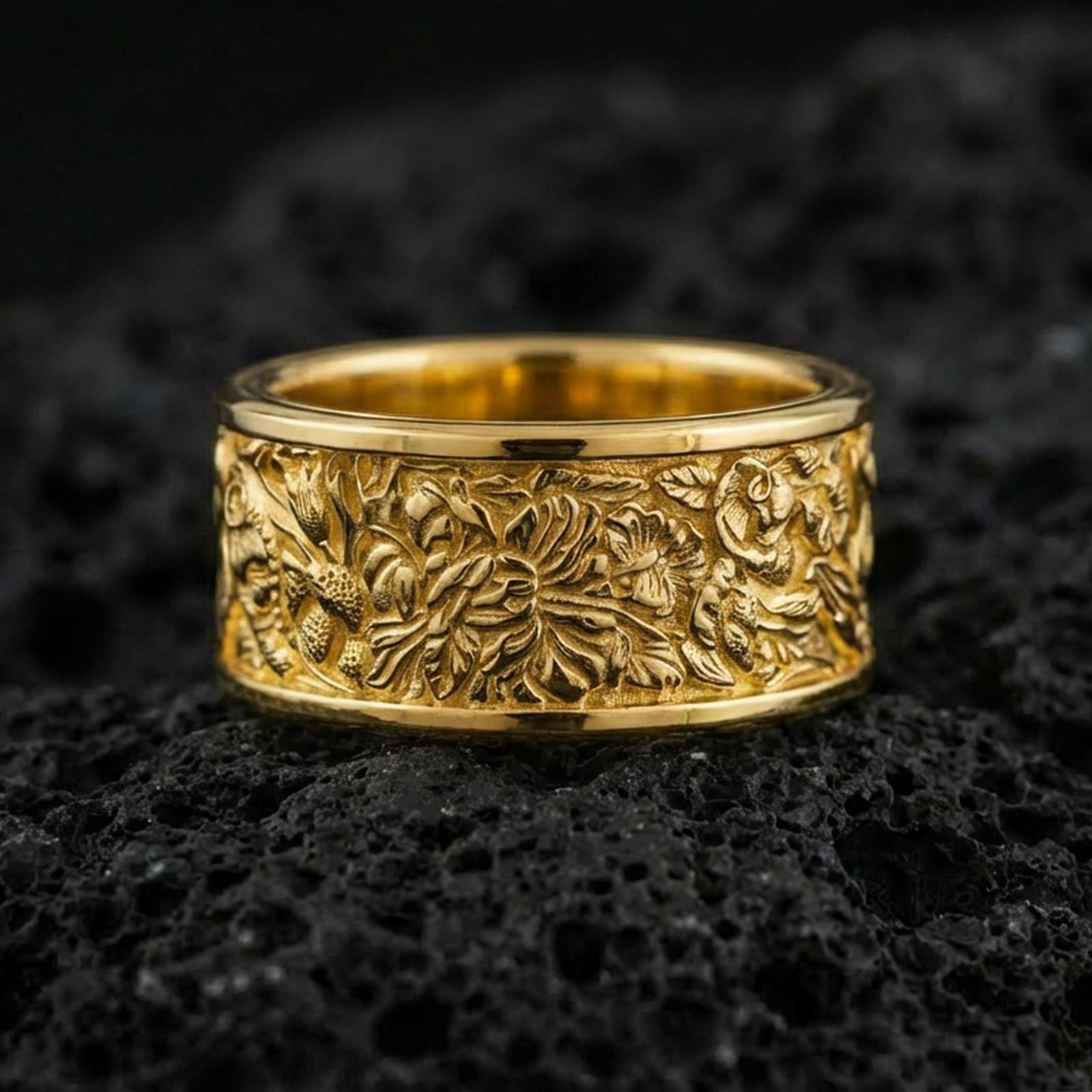 Gold plated jungle wildlife band ring on volcanic rock, detailed tropical foliage relief with animal engraving accents, luxury jewelry product photography.