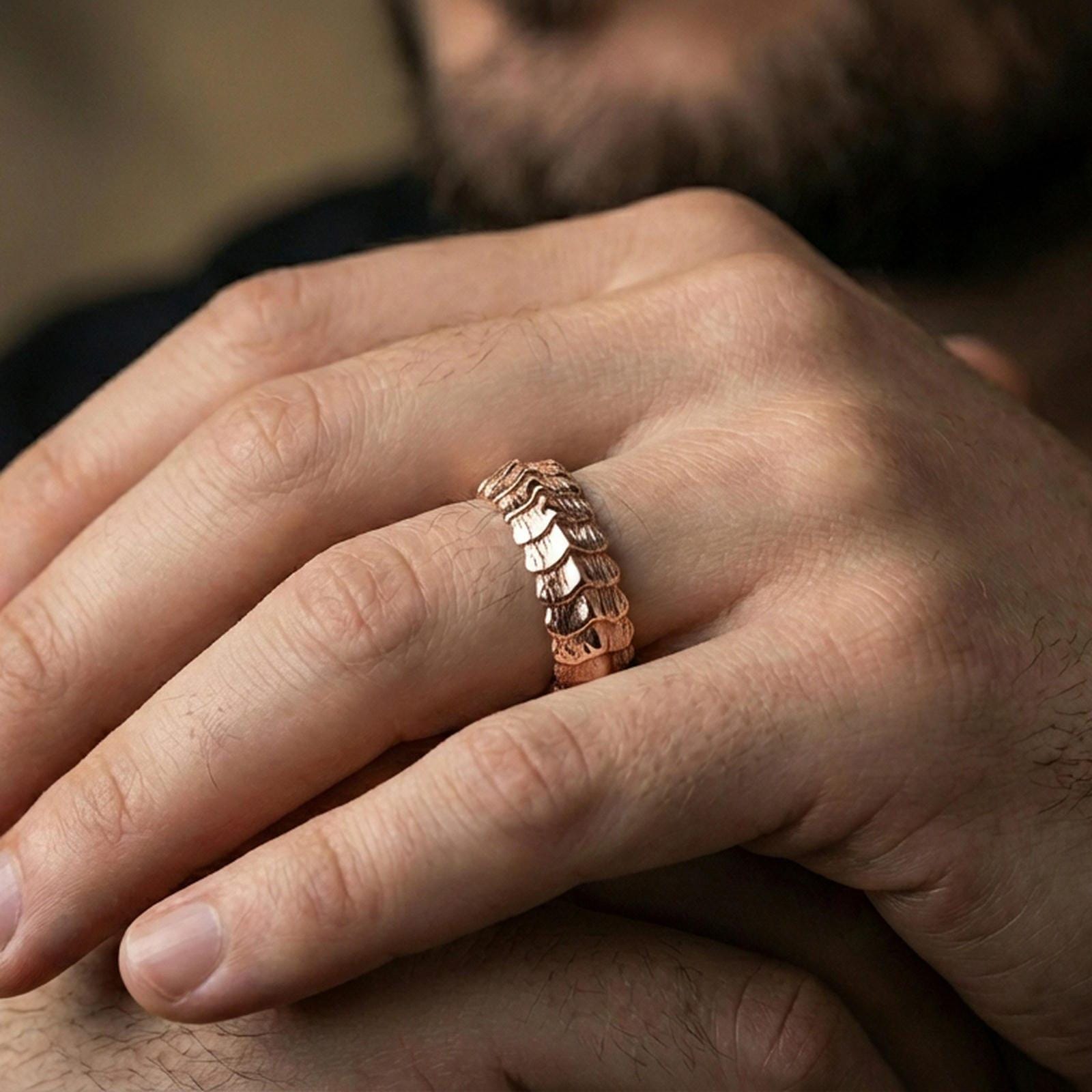 Rose gold plated dragon scale band ring worn on finger, sculpted layered ridge texture detail, elegant lifestyle wear shot.