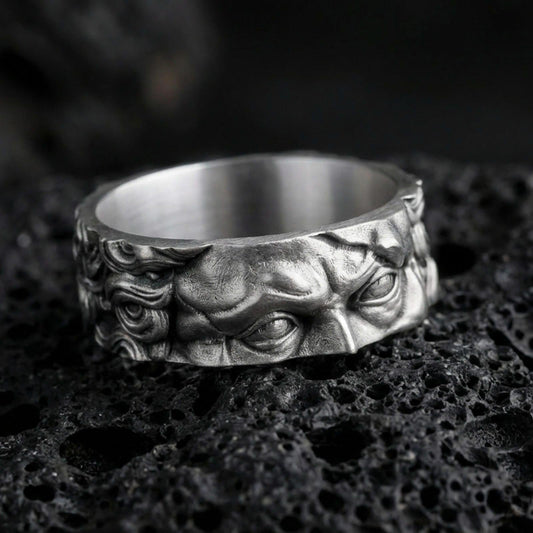 Oxidized sterling silver Michelangelo Moses spinner band ring on dark volcanic rock, Renaissance portrait relief on rotating center, premium macro product shot.