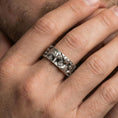 Load image into Gallery viewer, Oxidized sterling silver Michelangelo Moses spinner band worn on finger, portrait relief detail on rotating center, natural lifestyle hand shot with shallow depth of field.
