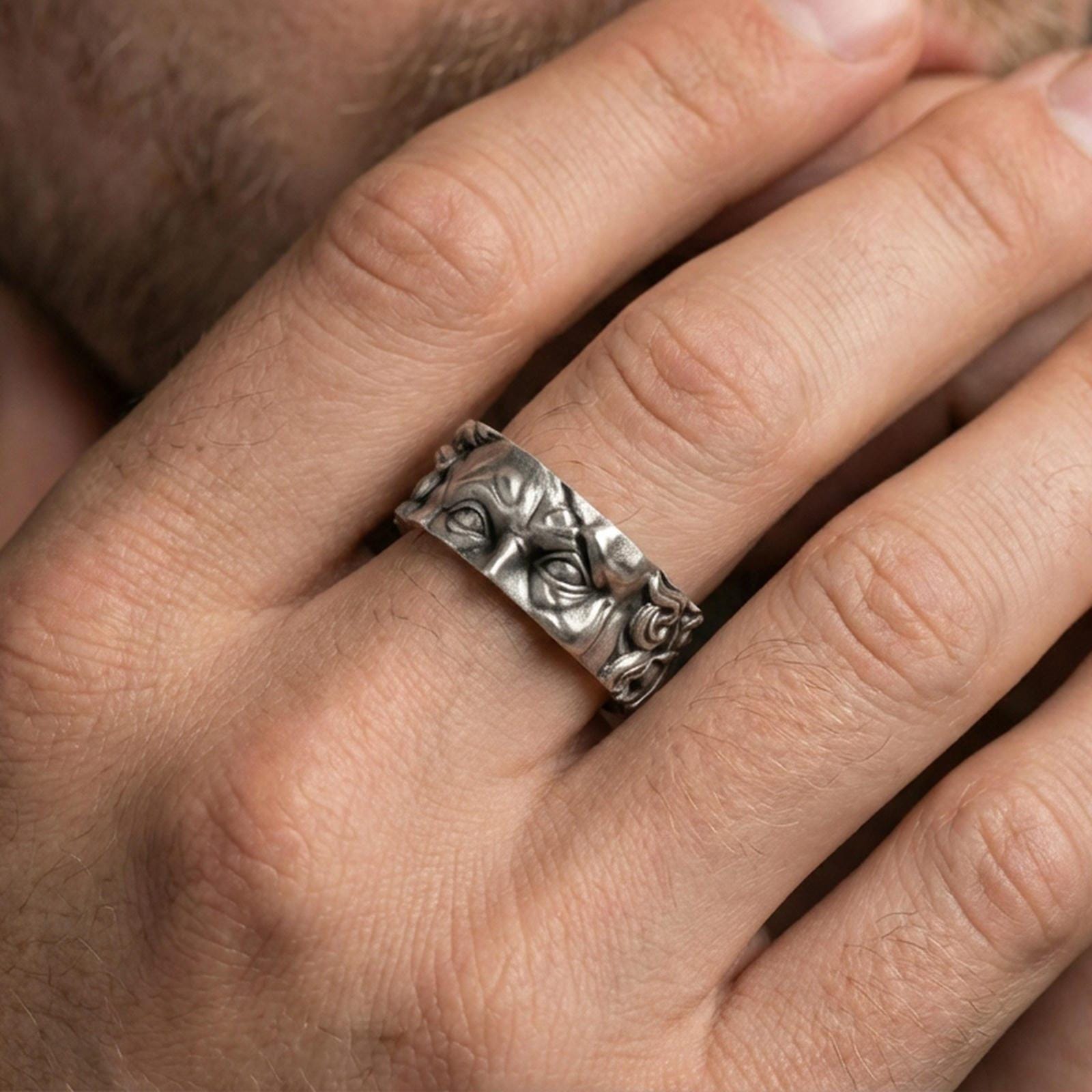 Oxidized sterling silver Michelangelo Moses spinner band worn on finger, portrait relief detail on rotating center, natural lifestyle hand shot with shallow depth of field.