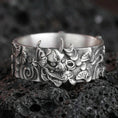 Load image into Gallery viewer, Oxidized sterling silver oni mask band ring on dark volcanic rock, Japanese demon face relief with swirling cloud motifs, premium macro product shot.
