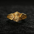 Load image into Gallery viewer, Gold plated Saint Jude signet ring on volcanic rock, detailed saint icon relief with “God Bless” and “Save Us” engraving, luxury jewelry product photography.
