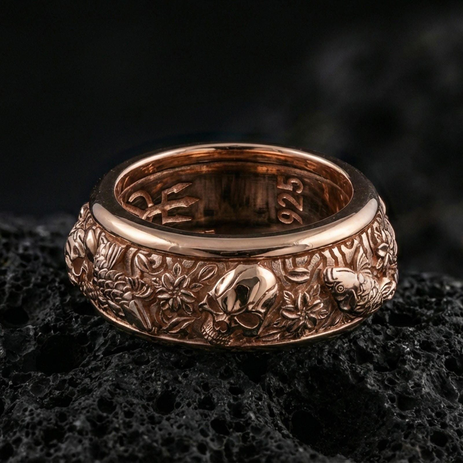 Rose gold plated sterling silver skull and koi spinner ring on volcanic stone, sculpted skull relief with carp and wave motifs in deep contrast, minimal high-end close-up.