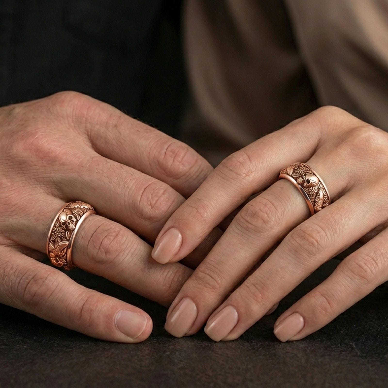 Rose gold plated skull and koi spinner ring worn on finger, sculpted skull relief with carp and wave detail, elegant lifestyle wear shot.