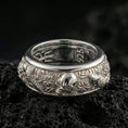 Load image into Gallery viewer, Polished silver skull and koi fidget spinner ring on black volcanic stone, crisp skull relief with carp and floral wave texture, centered close-up studio lighting.
