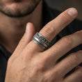 Load image into Gallery viewer, Oxidized sterling silver Last Supper engraved band worn on finger, apostle scene relief detail, natural lifestyle hand shot with shallow depth of field.
