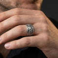 Load image into Gallery viewer, Oxidized sterling silver swirling flames band worn on finger, fire wave engraving detail, natural lifestyle hand shot with shallow depth of field.
