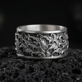 Load image into Gallery viewer, Oxidized sterling silver swirling flames band ring on dark volcanic rock, high-relief fire wave engraving with deep contrast, premium macro product shot.
