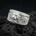 Load image into Gallery viewer, Polished silver lion signet ring on black volcanic stone, crisp lion head relief with detailed mane and engraved scrollwork sides, centered close-up studio lighting.
