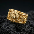 Load image into Gallery viewer, Gold plated lion head signet ring on volcanic rock, detailed roaring lion relief with baroque scrollwork shoulders and rope-edge accents, luxury jewelry product photography.
