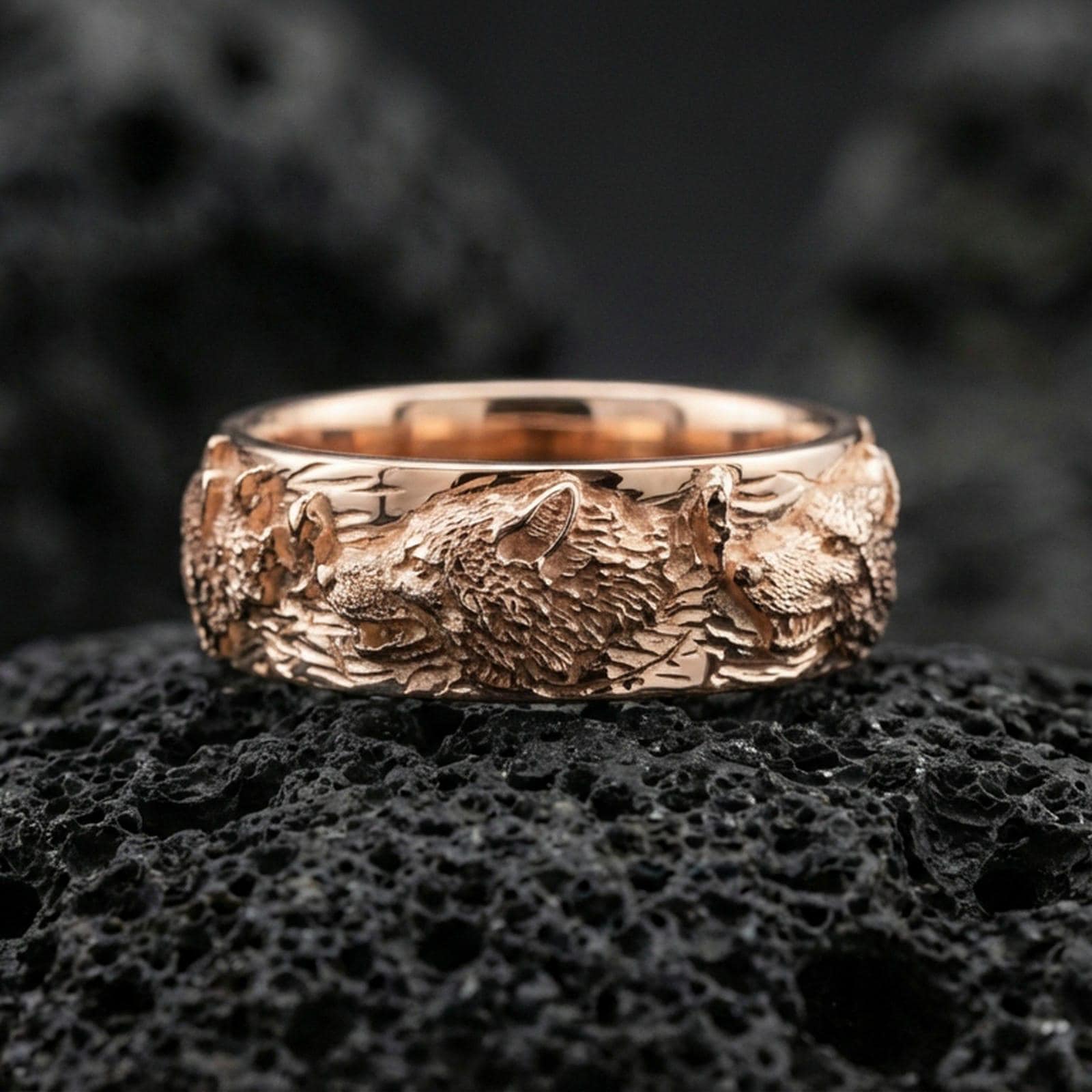 Rose gold plated wolf and deer band ring on black volcanic stone, detailed sculpted heads with warm metallic highlights, elegant product close-up.