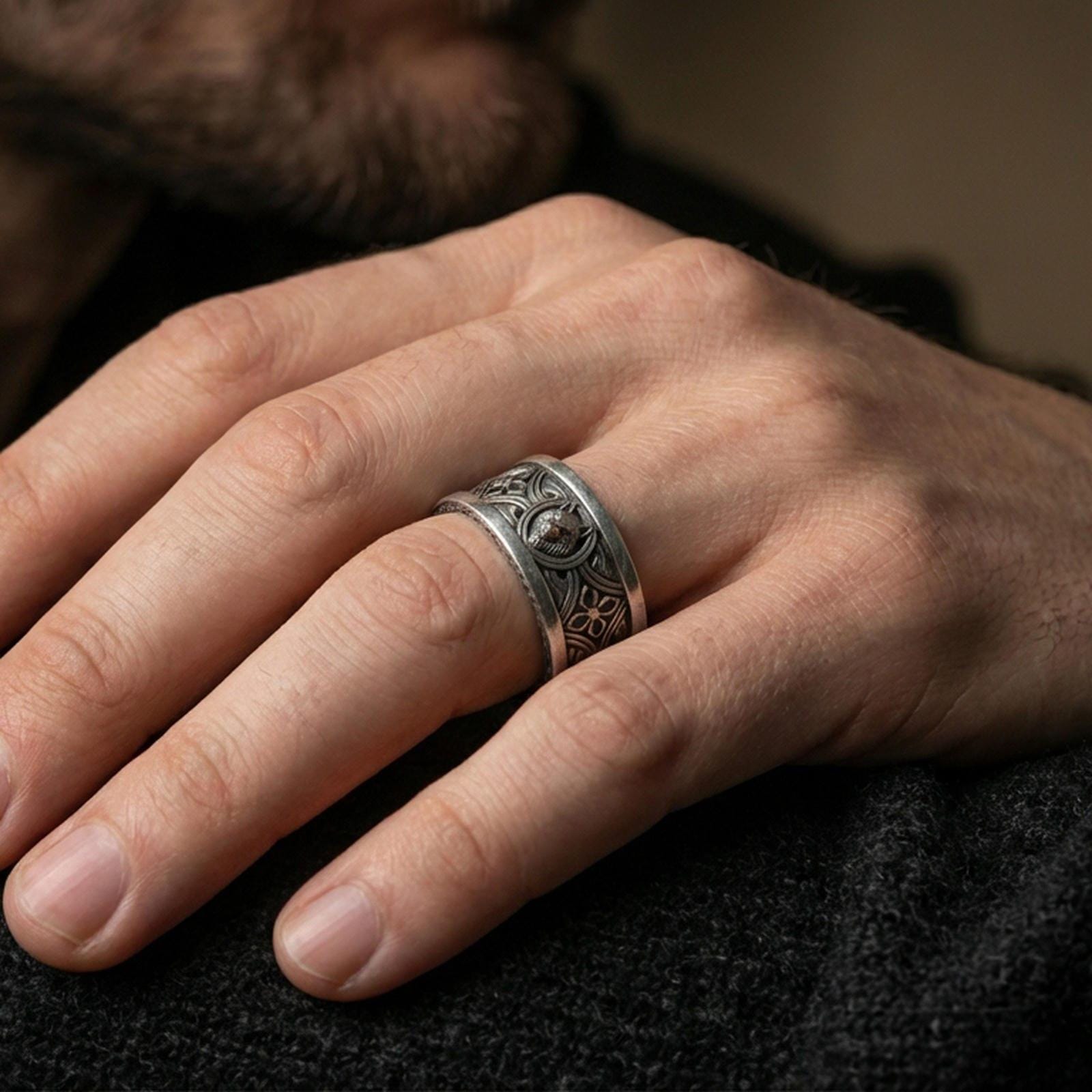 Oxidized sterling silver wolf ring worn on finger, Celtic knot band with dark recessed detailing and strong relief, lifestyle hand close-up.