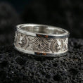 Load image into Gallery viewer, Polished silver wolf Celtic wedding band on dark volcanic stone, clean reflective edges and sharp engraved knotwork, premium close-up.
