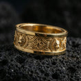 Load image into Gallery viewer, Gold plated wolf ring on volcanic rock, Celtic knot pattern with bold wolf emblems and rich metallic highlights, luxury studio macro.
