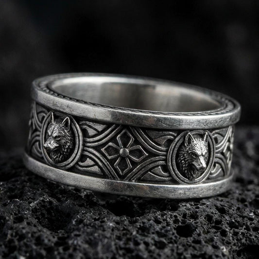 Oxidized sterling silver wolf ring on black volcanic rock, Celtic knot band with raised wolf medallions, crisp macro product photo with deep contrast.